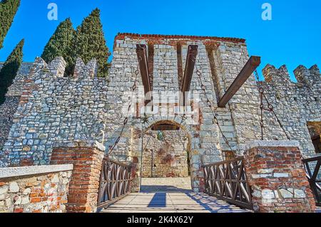 La porta medievale in pietra del Castello di Brescia con alte mura e merlature dai lati destro e sinistro della porta, Italia Foto Stock