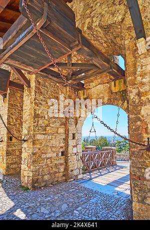 Conserva la porta medievale in pietra del Castello di Brescia con passo ad arco e ponte in legno sullo sfondo, Italia Foto Stock