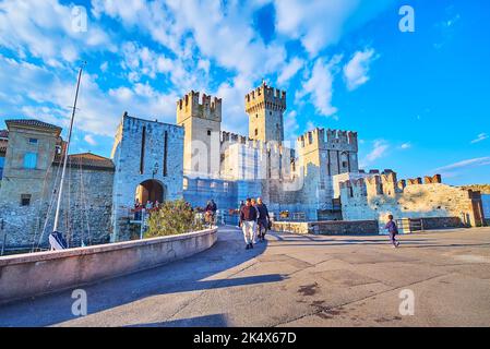 SIRMIONE, ITALIA - 10 APRILE 2022: Via al Castello Scaligero medievale con alte torri in pietra, cancello e mura conservate da Piazalle Porto, in AP Foto Stock