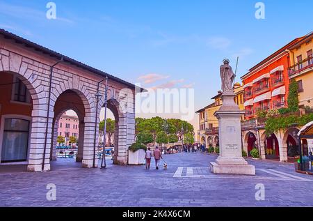 DESENZANO DEL GARDA, ITALIA - 10 APRILE 2022: Tramonto Piazza Giuseppe Malvezzi con case storiche, caffè e monumento a Sant'Angela Merici, Foto Stock