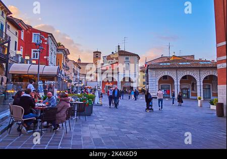 DESENZANO DEL GARDA, ITALIA - 10 APRILE 2022: Sera Piazza Giuseppe Malvezzi con affollate terrazze di ristoranti e bar, il 10 aprile a Desenzano Foto Stock