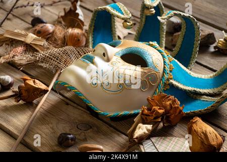 La maschera veneziana si trova su un tavolo di legno con carte di piume e bambole voodoo e oggetti sciamanici, mistero e misticismo Foto Stock