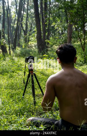 Ragazzo millenario meditando con l'allenatore online tramite la connessione iPad tablet, nella foresta, trasmettendo online la tua classe e le istruzioni, messico Foto Stock