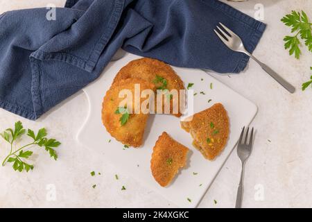 Polpettine di carne e foglie di prezzemolo su piatti di ceramica bianca in una cucina da banco. Foto Stock