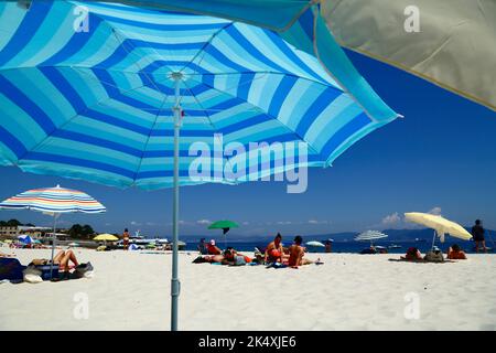 Ombrelloni e turisti sulla famosa spiaggia di Playa de Rodas sulle Isole Cies, Galizia, Spagna nordoccidentale. Foto Stock