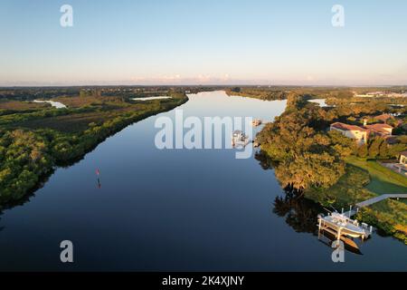 La vista degli alberi sulle coste del fiume Manatee sotto il cielo blu riflesso nell'acqua Foto Stock