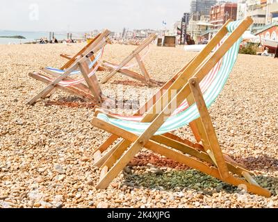 Sedie a sdraio pieghevoli a strisce rosse e verdi con strisce bianche sulla spiaggia di Brighton. Foto Stock