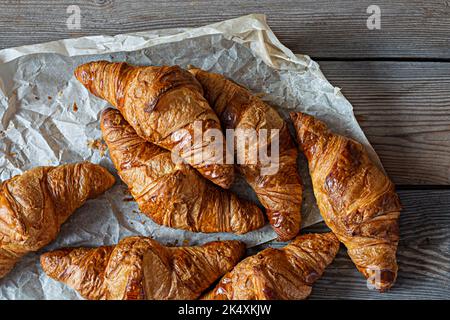 Croissant francesi freschi e croccanti su uno sfondo di legno. Tradizionale pasta sfoglia (panini) per colazione, delizioso dessert. Foto Stock