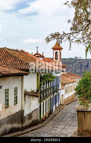 Strada acciottolata nella città di Diamantina con le sue case in stile coloniale e colorati balconi con il campanile della chiesa sullo sfondo Foto Stock