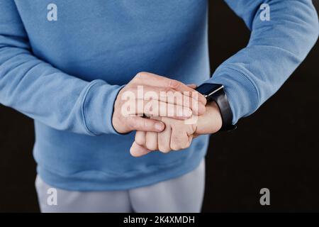 Minimo primo piano dello smartwatch uomo che controlla su sfondo nero, spazio copia Foto Stock