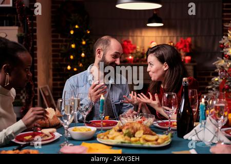 Coppia che chiacchiera alla festa domestica di natale della famiglia, che parla al tavolo di festa della cena, che mangia il cibo tradizionale. Moglie e marito che hanno conversazione, celebrazione Natale vacanza invernale Foto Stock