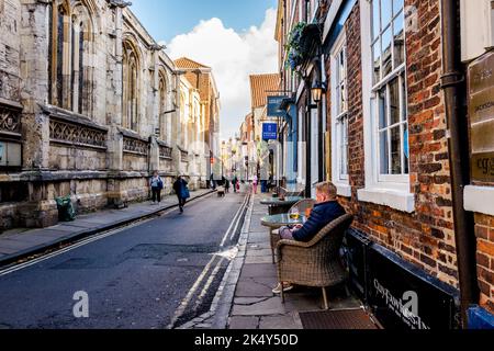 Cliente maschio seduto su una sedia di vimini fuori del Guy Fawkers Inn, casa pubblica o pub con una birra e un telefono cellulare nella città di York, Yorkshire. Foto Stock