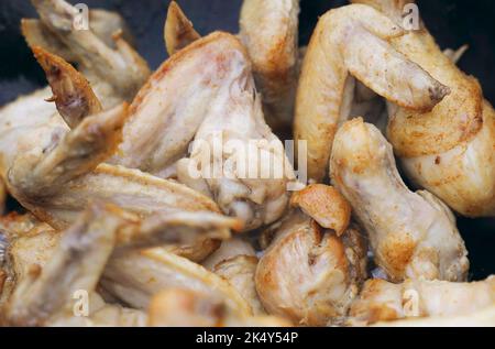 Il cuoco prepara il pollo - cosce e ali in un calderone all'aria aperta. Primo piano. Foto Stock