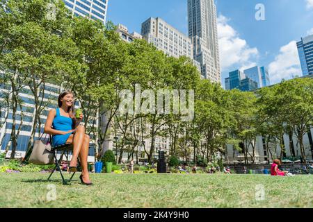 New York, Bryant Park, Manhattan. Vita di New York City. Multiculturale giovane professionista bere succo di frullato verde in estate Foto Stock