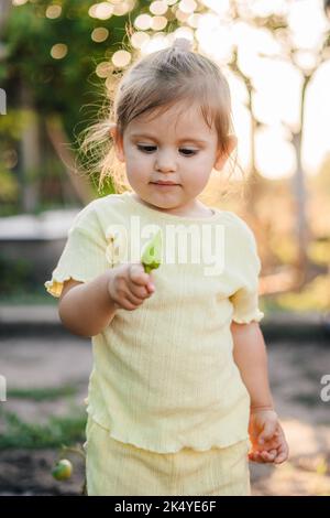 Ritratto di un'adorabile bambina che tiene in mano un pepe recentemente raccolto dal giardino estivo di sua nonna. Crescere cibo naturale biologico fresco e Foto Stock