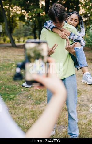 Amico che registra il video di adolescenti e ragazzi che ballano e per i social media. Pieno di gioia. Persone attive e positive per i Millennial. Posa per una clip divertente. Foto Stock