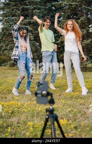 Gli adolescenti stanno filmando video di danza con un telefono nel parco estivo. Sfida dei social media. Il concetto di ballerino, influencer, artista dei social media. Foto Stock