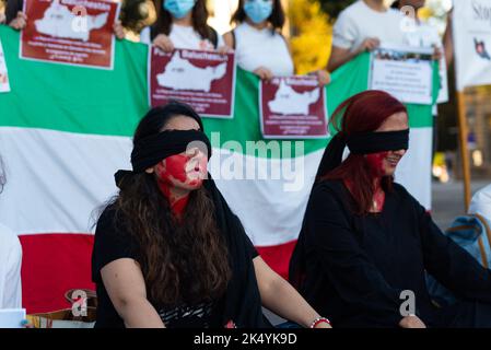 Barcellona, Spagna. 04th Ott 2022. Le donne siedono bendate e dipinte in rosso contro la bandiera iraniana a Barcellona, in Spagna, il 04 ottobre 2022. Manifestazioni sono state tenute in città di tutto il mondo per protestare contro l'incarcerazione e l'uccisione da parte della polizia morale iraniana di Mahsa Amini per non aver indossato correttamente in pubblico. Credit: Sipa USA/Alamy Live News Foto Stock