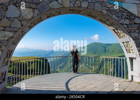 Un uomo si trova sull'Arco dell'amicizia, sulla Georgian Military Highway Foto Stock