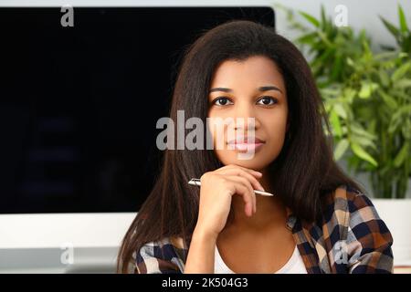 Premuroso focalizzato bella donna afro con penna Foto Stock