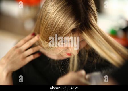 Giovane donna bionda dimostra radici di capelli ricrescita Foto Stock