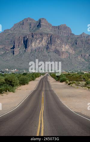 In piedi su una strada diritta che conduce alle Superstition Mountains Foto Stock