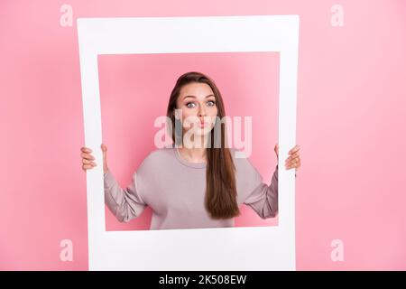 Foto di bella dolce donna mano tenere bianco carta foto vestita elegante pullover inviare Kiss fotocamera isolato su sfondo di colore rosa Foto Stock