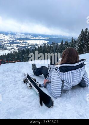 Foto di una sciatrice seduta sulla pista di sci riposante attività di svago estrema e di stile di vita attivo. Sciatore femminile su un pendio in montagna. Sport invernale Scratere di campagna nelle Alpi Foto Stock