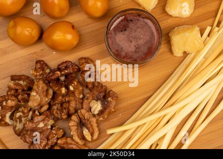 Varie varietà di formaggi, noccioli, uova di quaglia affumicate e miele in un vaso di vetro su una superficie di legno. Foto Stock
