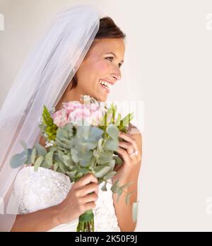 Pronto per il suo grande giorno. Bella giovane sposa guardando lontano mentre tiene il suo bouquet. Foto Stock