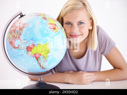 La geografia è la sua specialità. Un insegnante di geografia piuttosto giovane che sorride accanto a un globo della terra. Foto Stock