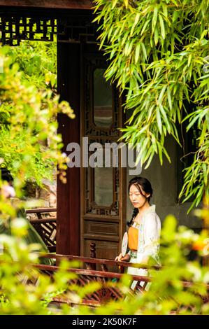 Una ragazza vestita con abiti tradizionali nei terreni del giardino di coppia, patrimonio dell'umanità dell'UNESCO, Suzhou, Provincia di Jiangsu, Cina. Foto Stock
