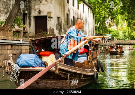 Un barcaiolo che voga una barca turistica sul fiume Pingjiang lungo Pingjiang Lu una strada piena di edifici di vecchio stile a Suzhou, Provincia di Jiangsu, Cina. Foto Stock