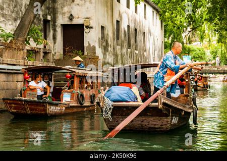 Un barcaiolo che voga una barca turistica sul fiume Pingjiang lungo Pingjiang Lu una strada piena di edifici di vecchio stile a Suzhou, Provincia di Jiangsu, Cina. Foto Stock