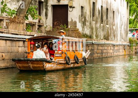 Donne vestite con abiti tradizionali fotografando con i telefoni cellulari su una barca turistica sul fiume Pingjiang lungo Pingjiang Lu una strada piena di o Foto Stock