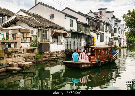 Donne vestite con abiti tradizionali su una barca turistica sul fiume Pingjiang lungo Pingjiang Lu una strada piena di edifici di vecchio stile a Suzhou, Jiang Foto Stock