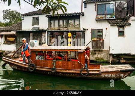 Un barcaiolo che voga una barca turistica sul fiume Pingjiang lungo Pingjiang Lu una strada piena di edifici di vecchio stile a Suzhou, Provincia di Jiangsu, Cina. Foto Stock