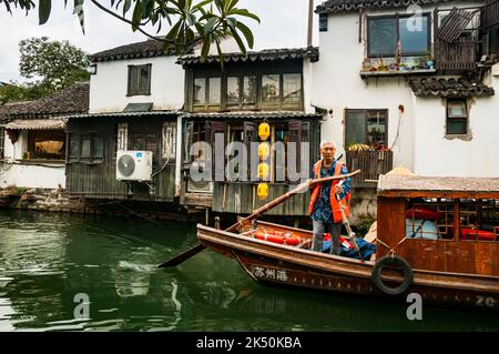 Un barcaiolo che voga una barca turistica sul fiume Pingjiang lungo Pingjiang Lu una strada piena di edifici di vecchio stile a Suzhou, Provincia di Jiangsu, Cina. Foto Stock