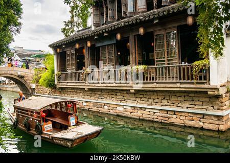 Una barca turistica che passa davanti ad una casa da tè sul Fiume Pingjiang lungo Pingjiang Lu una strada piena di edifici di vecchio stile a Suzhou, nella Provincia di Jiangsu, Cina Foto Stock