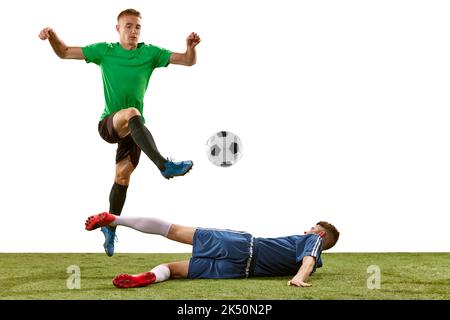 Giocatori di calcio che si sfidano per la palla sul pavimento in erba su sfondo bianco. Concetto di sport, azione, competizione, partita di calcio Foto Stock