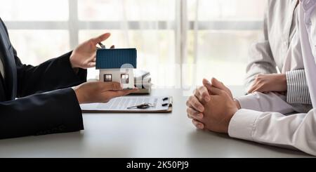 Agente immobiliare che presenta ad una coppia un modello di casa di proprietà di progetto. Foto Stock