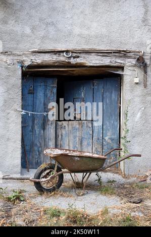 Old Barn porta e Rusty Wheelbarrow Foto Stock