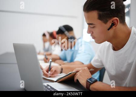 Studio, notebook e laptop con studenti in aula universitaria, biblioteca o spazio di lavoro per l'apprendimento, l'istruzione e gli esami. Giovani universitari Foto Stock