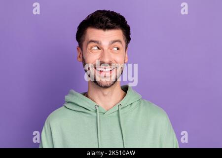 Primo piano foto di giovane divertente eccitato uomo sopportato toothy sorriso sognante sguardo interessato informazioni spazio vuoto isolato su sfondo di colore viola Foto Stock