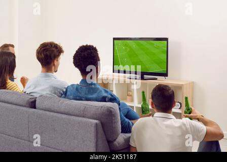 Gruppo di amici diversi seduti sul divano, guardando il calcio in TV e bevendo birra Foto Stock