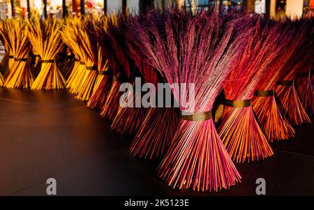 Prodotto fatto a mano in erba dura verniciato in rosso e giallo legato al centro come forma conica in piedi sul pavimento. Foto Stock