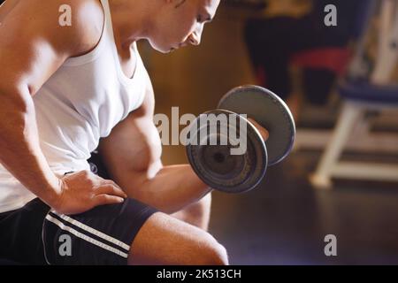 Prova che il lavoro duro paga fuori. Un giovane uomo bello che solleva i pesi. Foto Stock