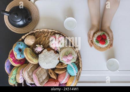 Cibo giocattolo lavorato a maglia da filato. Dolci, dolci, biscotti e torte. Foto Stock