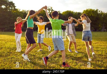 Gruppo di bambini felici che giocano, ballano e si divertono nel parco Foto Stock