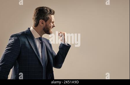 Uomo d'affari aggressivo in tuta minacciare il gesto scuotendo pugno a qualcuno, minacciando Foto Stock